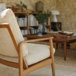 Fauteuil vintage scandinave dans un petit salon lumineux, bois clair, tissu crème